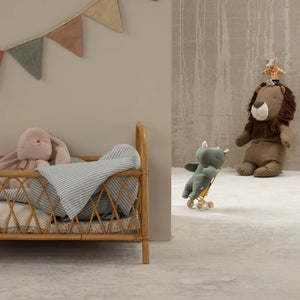 Cozy nursery scene featuring plush toys including a rabbit and lion, with a cute stuffed elephant on wheels.