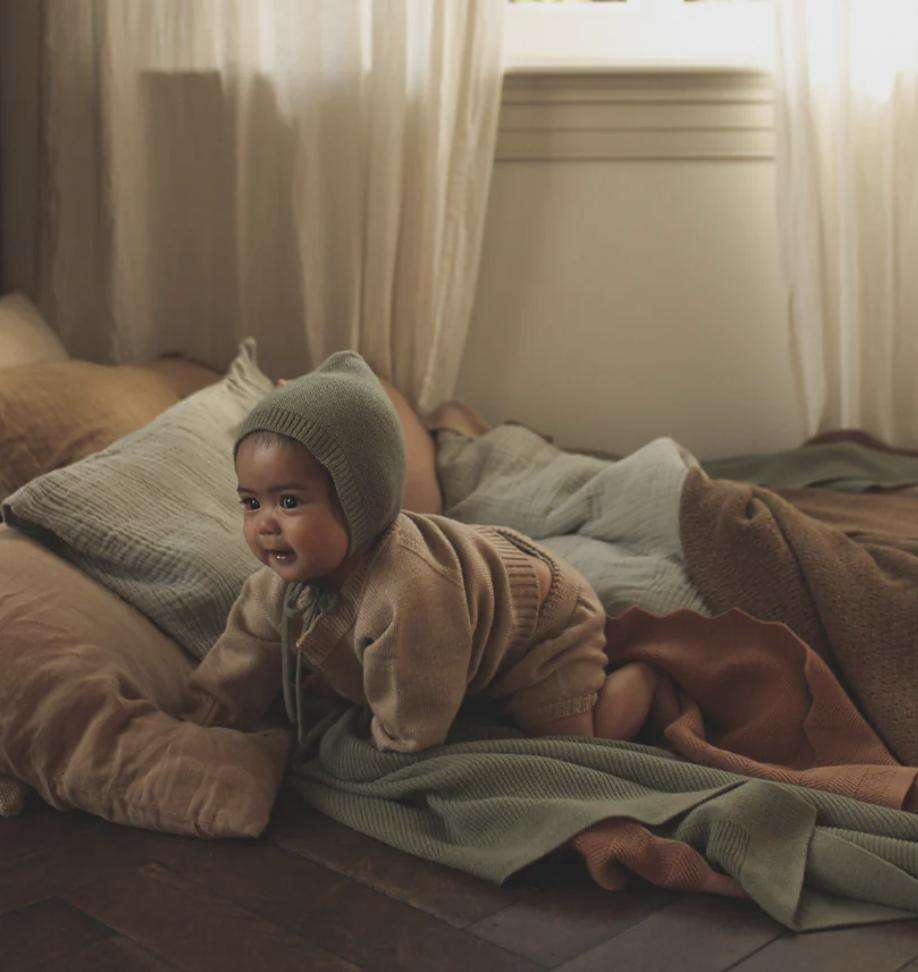 Baby in Strickjacke und Hose aus der Babykleidung-Kollektion 0–24 Monate
