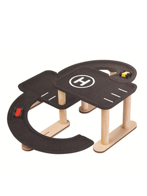 Kind lässt ein Auto die Rampe der PlanToys Parkgarage hinunterfahren