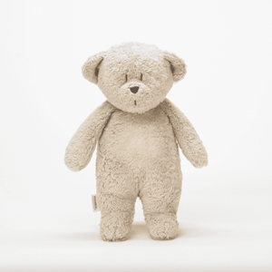Baby kuschelt mit dem Moonie 2.0 Humming Bear in Sand