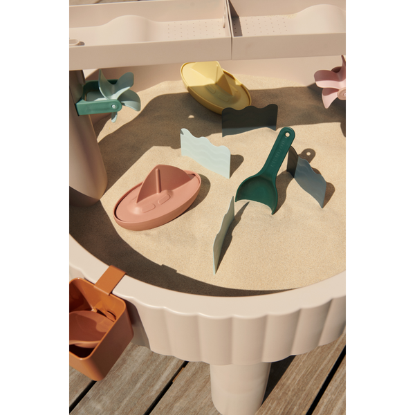 Sepp Outdoor-Aktivitätstisch Sandy mit bunten Förmchen und Spielsachen im Sandbereich.