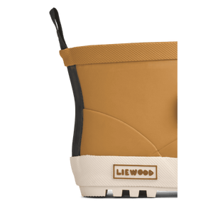 Kind trägt die Golden Caramel Regenstiefel Jesse Bear von Liewood