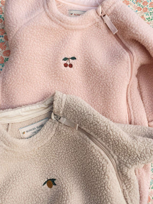 Zwei Pile-Fleece-Einteiler in Rosa und Creme nebeneinander