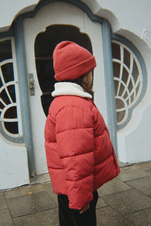 Kind trägt die rote Avely Mütze von Konges Sløjd zur Winterjacke
