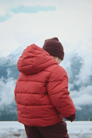 Kind in der roten Winterjacke Alpi von Konges Sløjd im Schnee