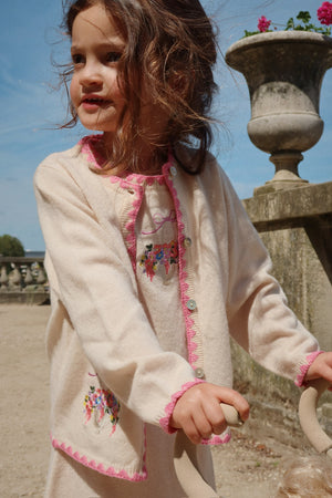 Young girl wearing Collette Strick-Cardigan off white with floral embroidery on a sunny day.