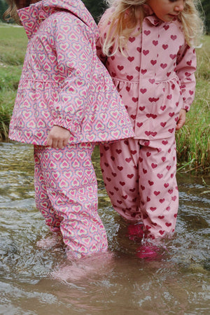 Kinder im Palme Regenset Amour Pink spielen im Wasser