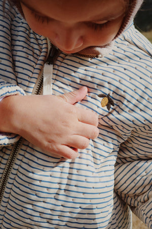 Child wearing Thermojacke Stripe Bluie, showcasing soft fleece lining and bee embroidery detail.